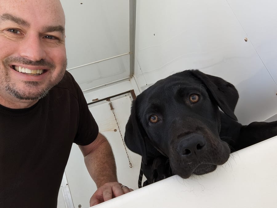 Paul with a calm black Lab in the Hurricane Bath trailer