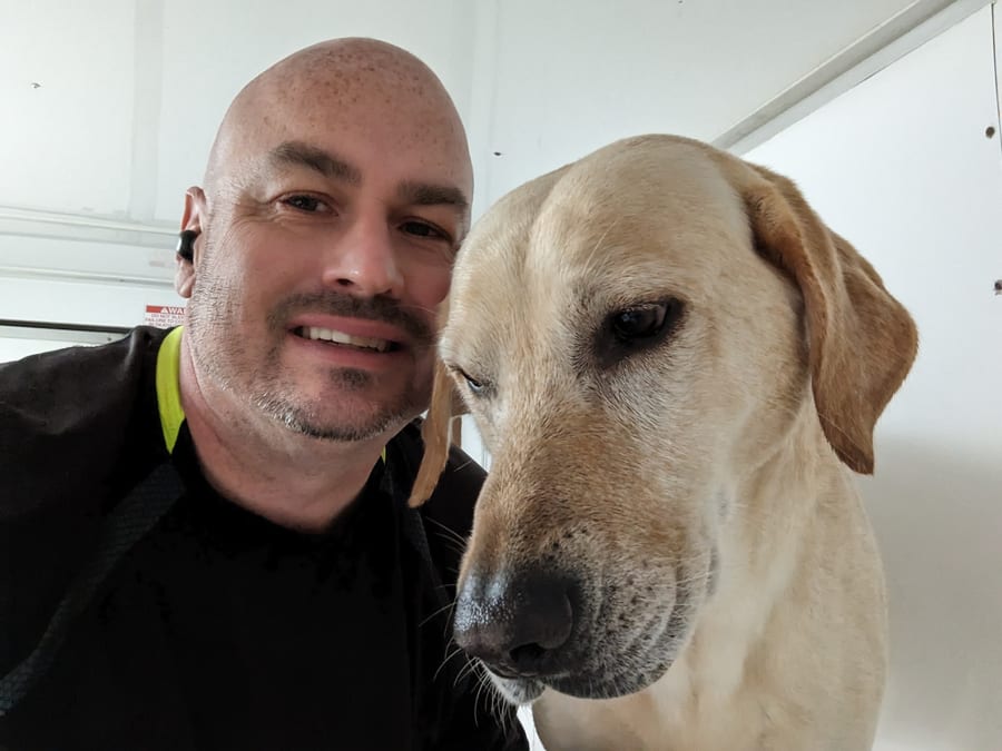 Paul with a relaxed yellow Lab in the trailer