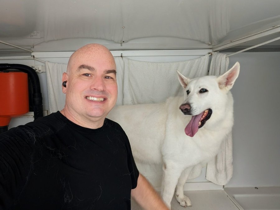 Paul with a happy white German Shepherd in the bright trailer